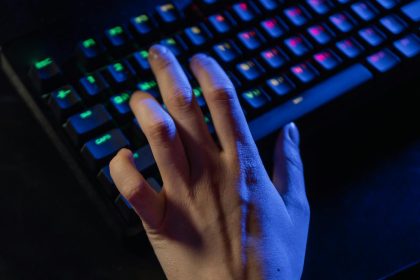 A hand resting on a colorful RGB gaming keyboard, highlighting vibrant illumination.