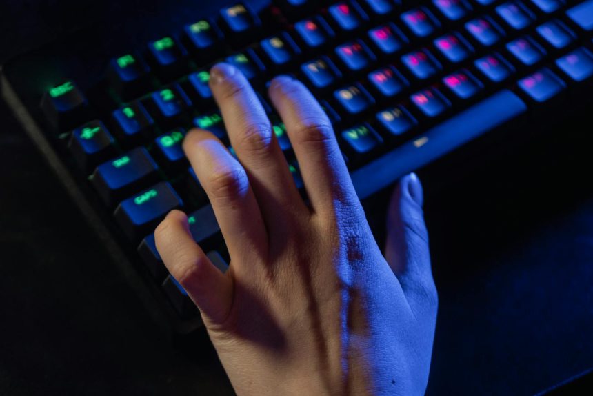 A hand resting on a colorful RGB gaming keyboard, highlighting vibrant illumination.